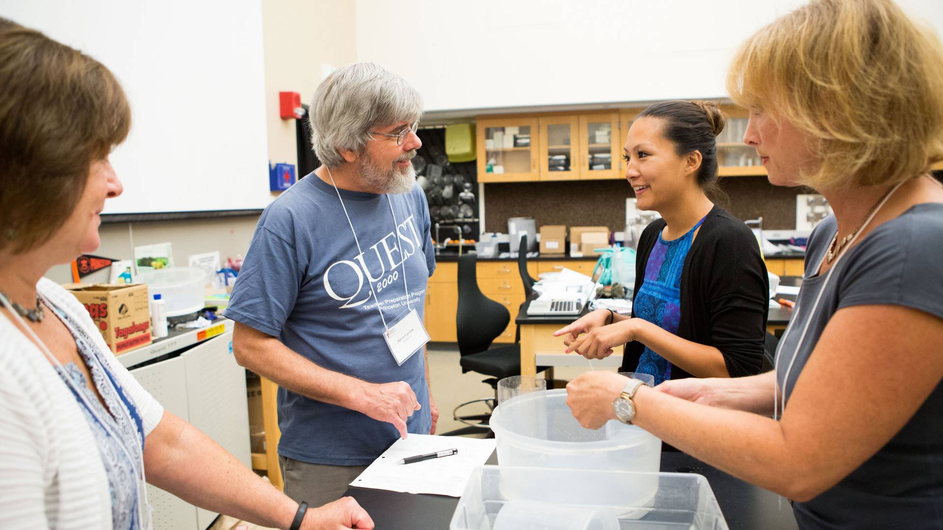 Four QUEST participants stand during a lesson and speak