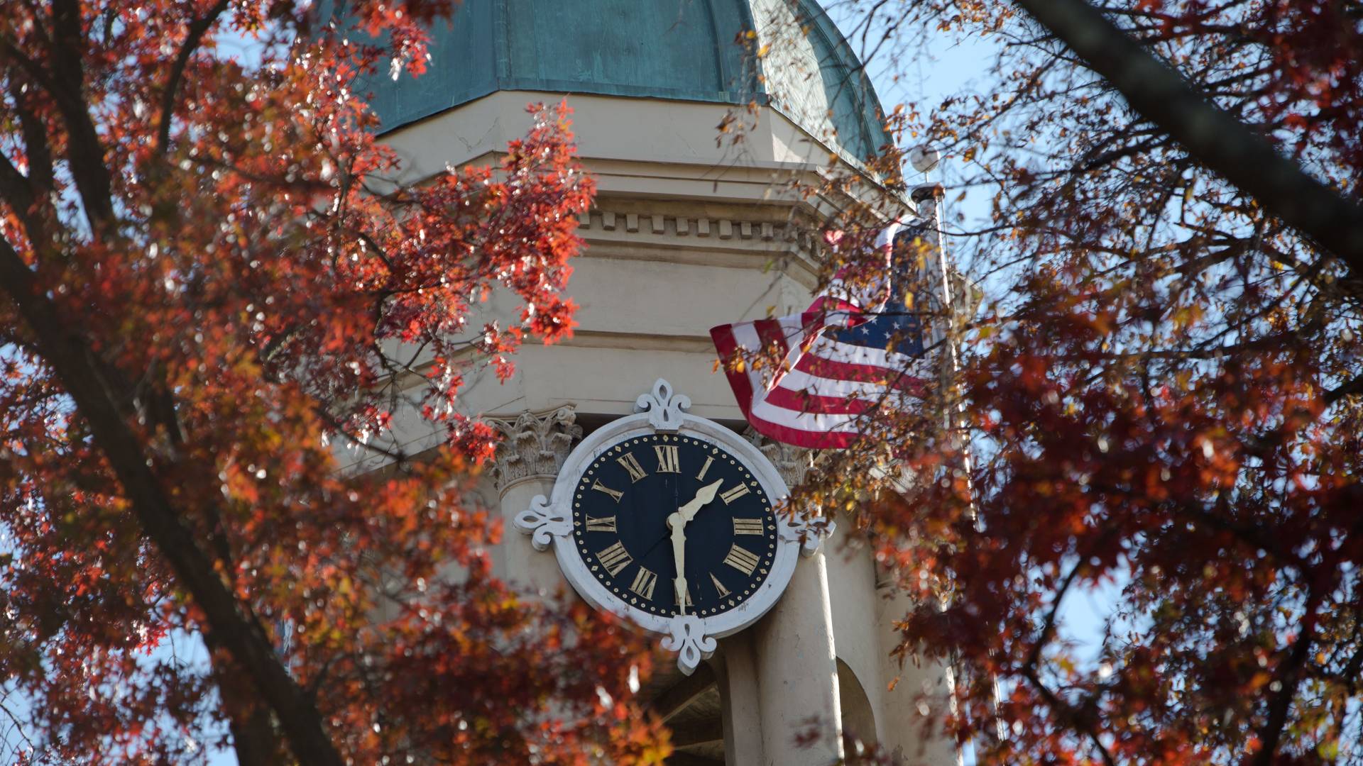 The cupola of Nassau Hall showing its clock and an American flag