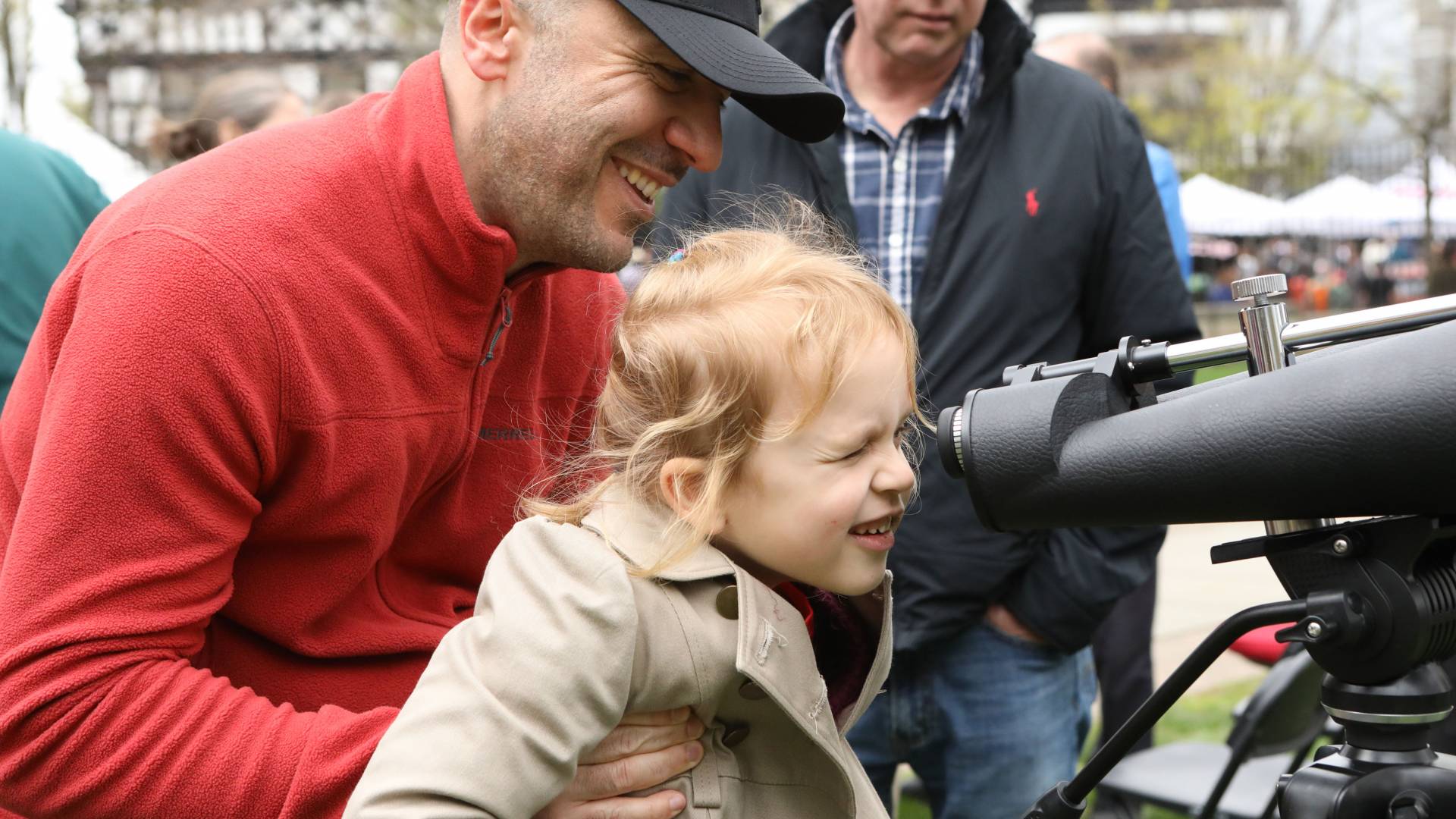 Flip Beranyeh holding Krystina to look through telescope