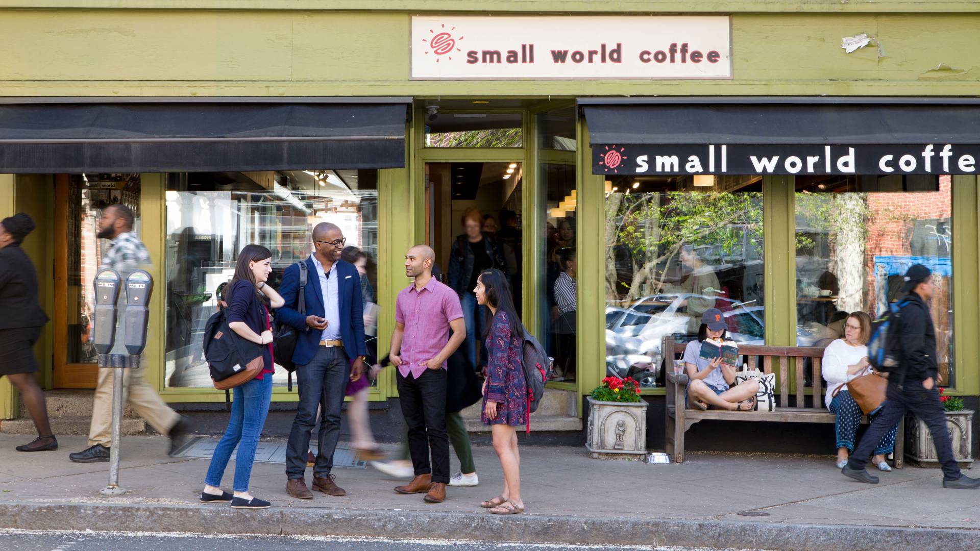 Frederick Wherry standing with students in front of coffee shop with people walking by