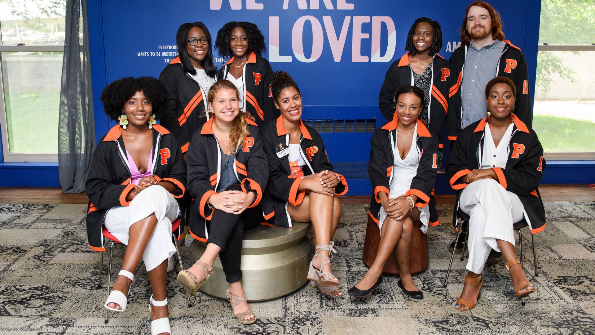 Students sitting in front of wall that says "loved"