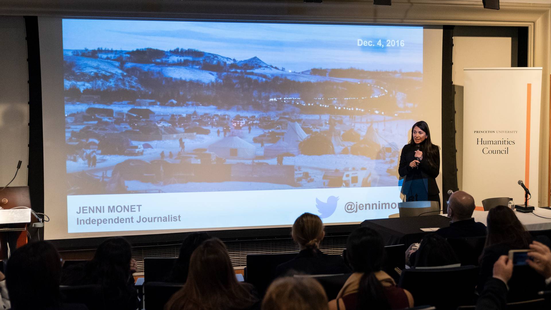 Jenni Monet speaks in front of a projected slide