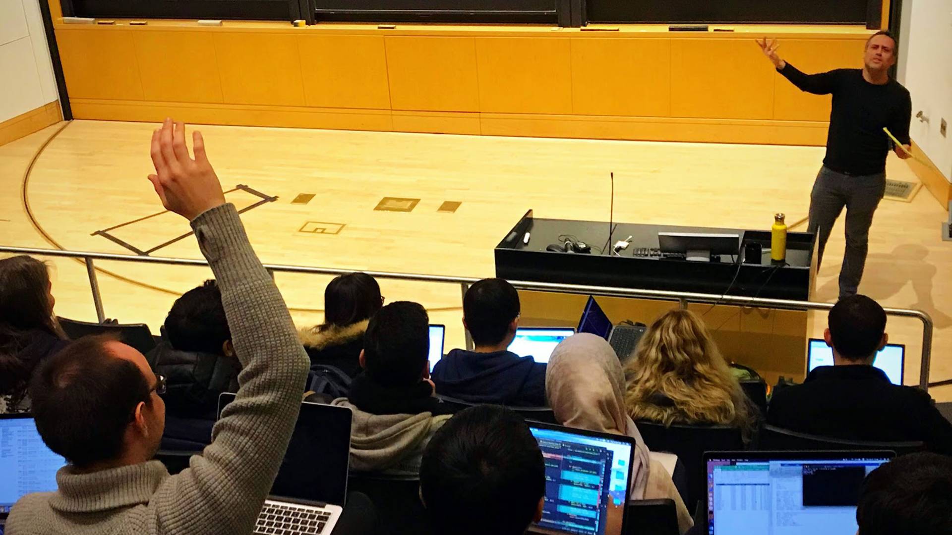 Gabe Perez-Giz standing before class answering a question from a student with a raised hand