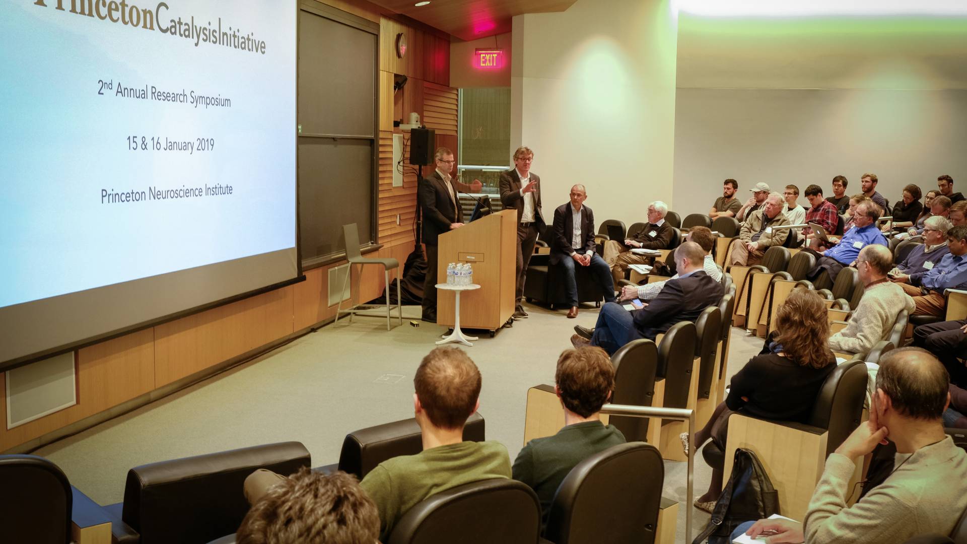 Paul Chirik and David Macmillan at a podium, answering questions from the audience