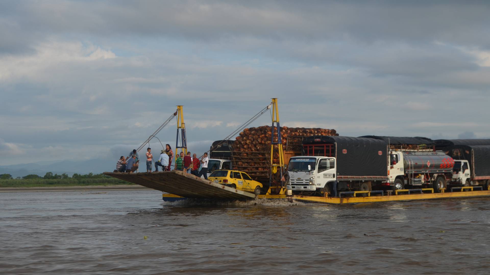 Barge filled with cars, trucks and people going across river
