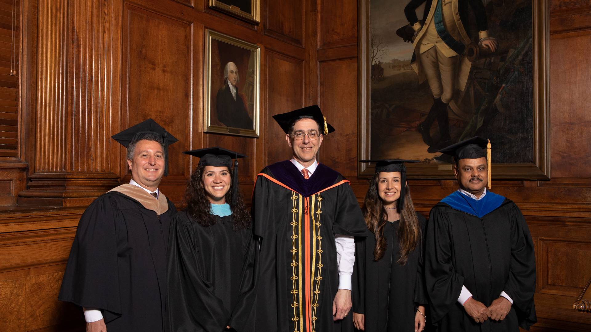 Kevin Killian, Kimberly Dickstein, Petrina Plunkett and Dr. Arun Srivastava pose with Christopher L. Eisgruber in ceremonial black gowns and mortarboards
