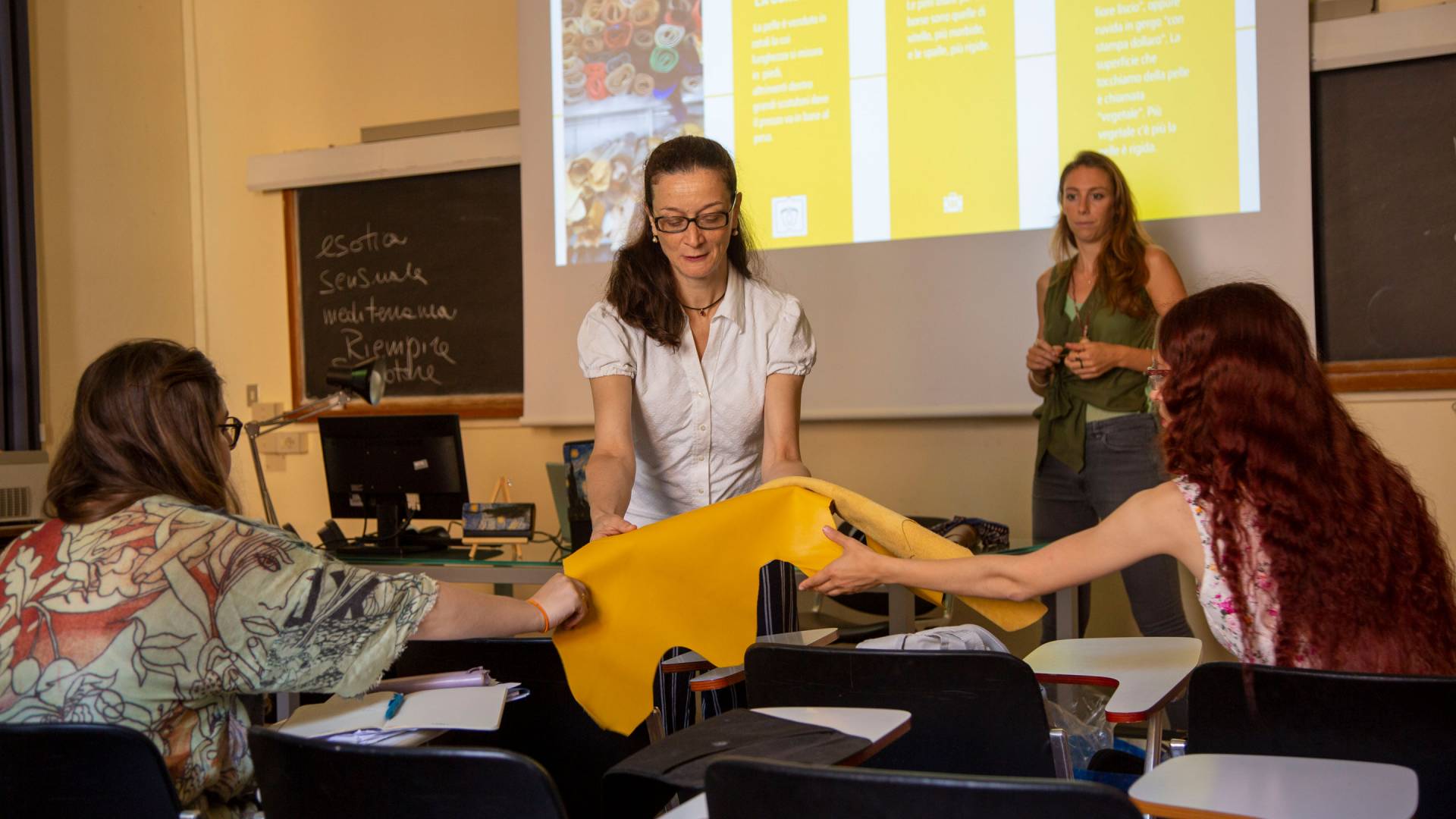 Student holding a sample of fabric in front of an Italian entrepreneur