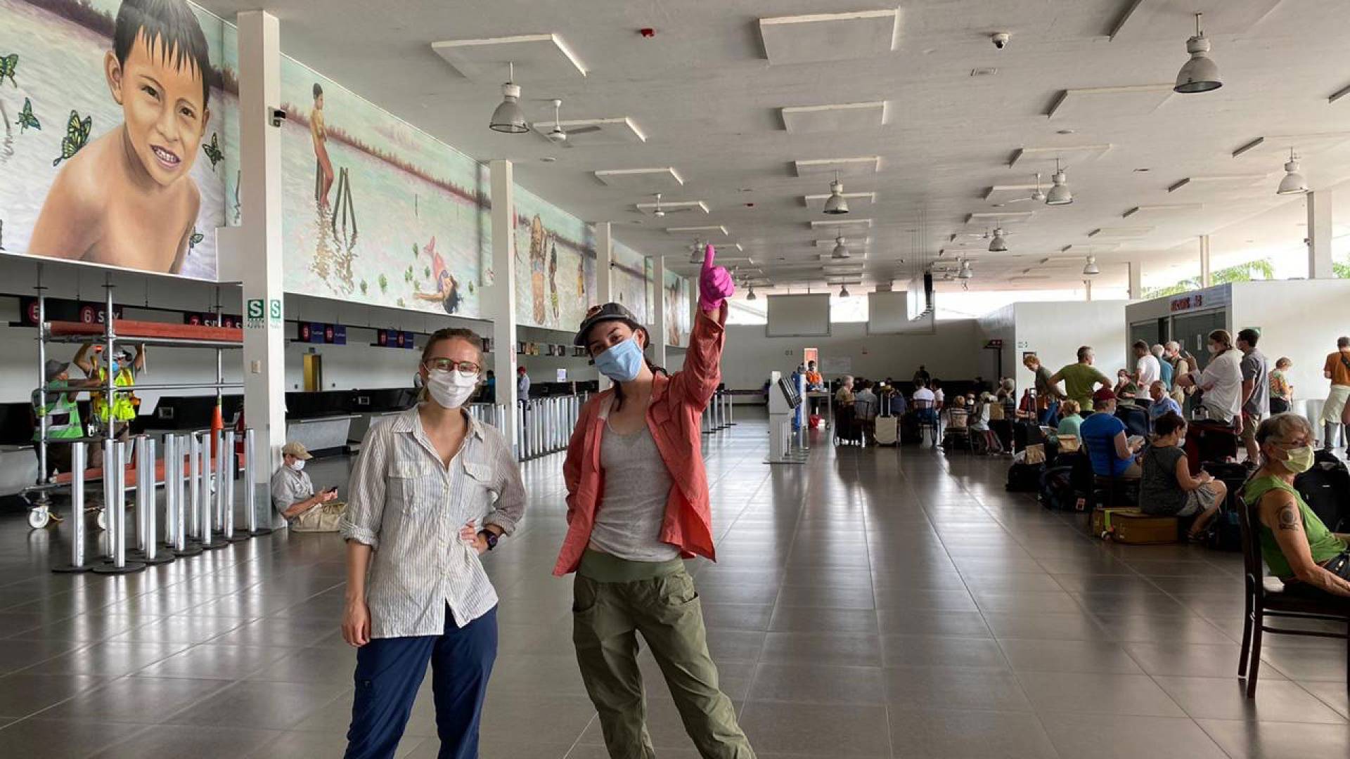 Julie Tierney on right with baseball cap and Kara Fokrig (grad student from Cornell) standing in airport waiting for flight.