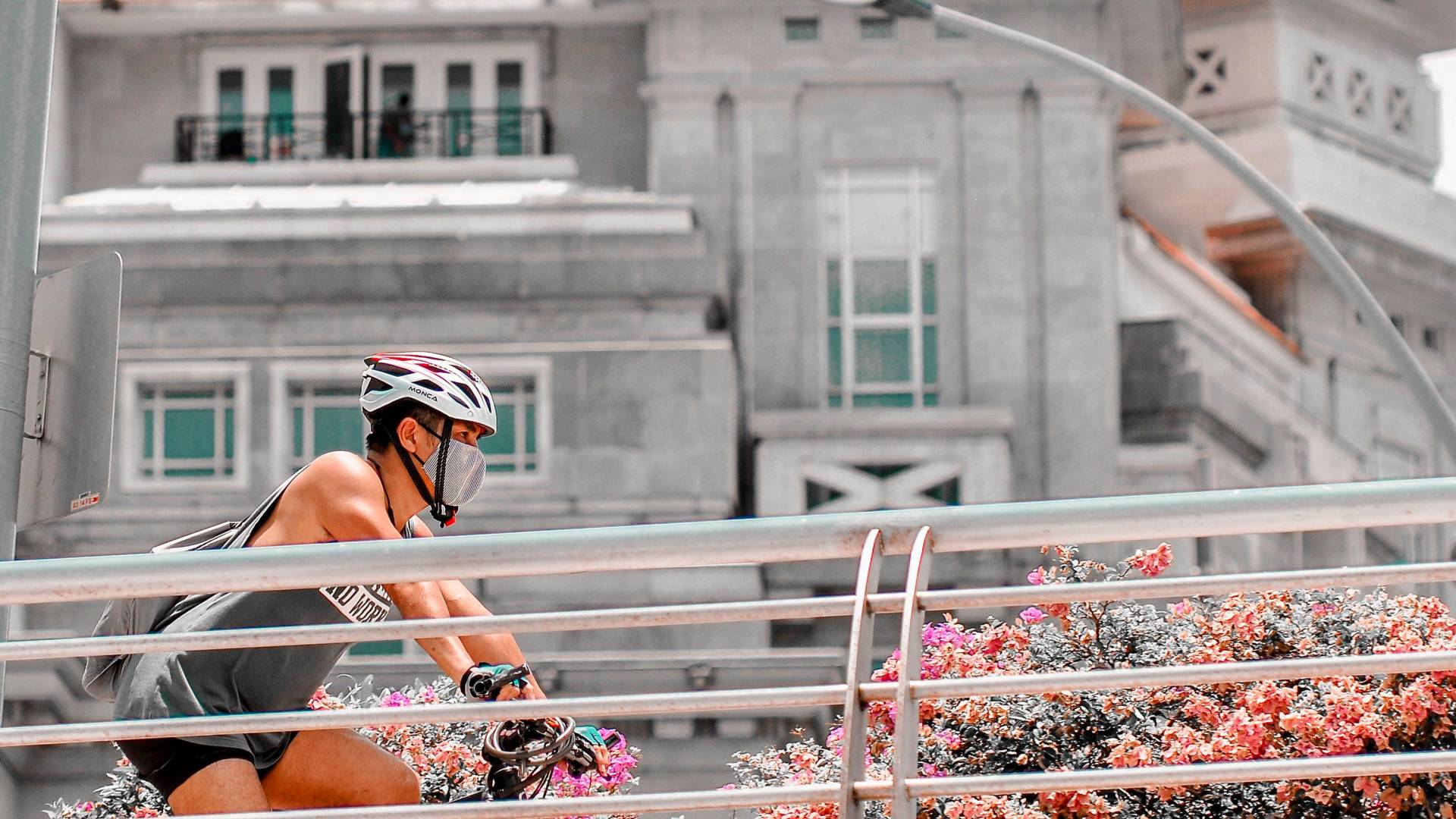 A woman wearing a mask bicycles up a ramp