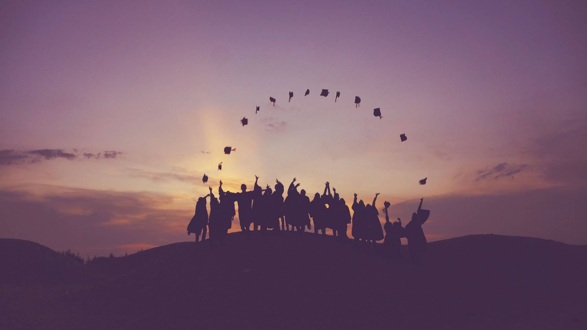 Students in their gowns, throwing up their mortarboards