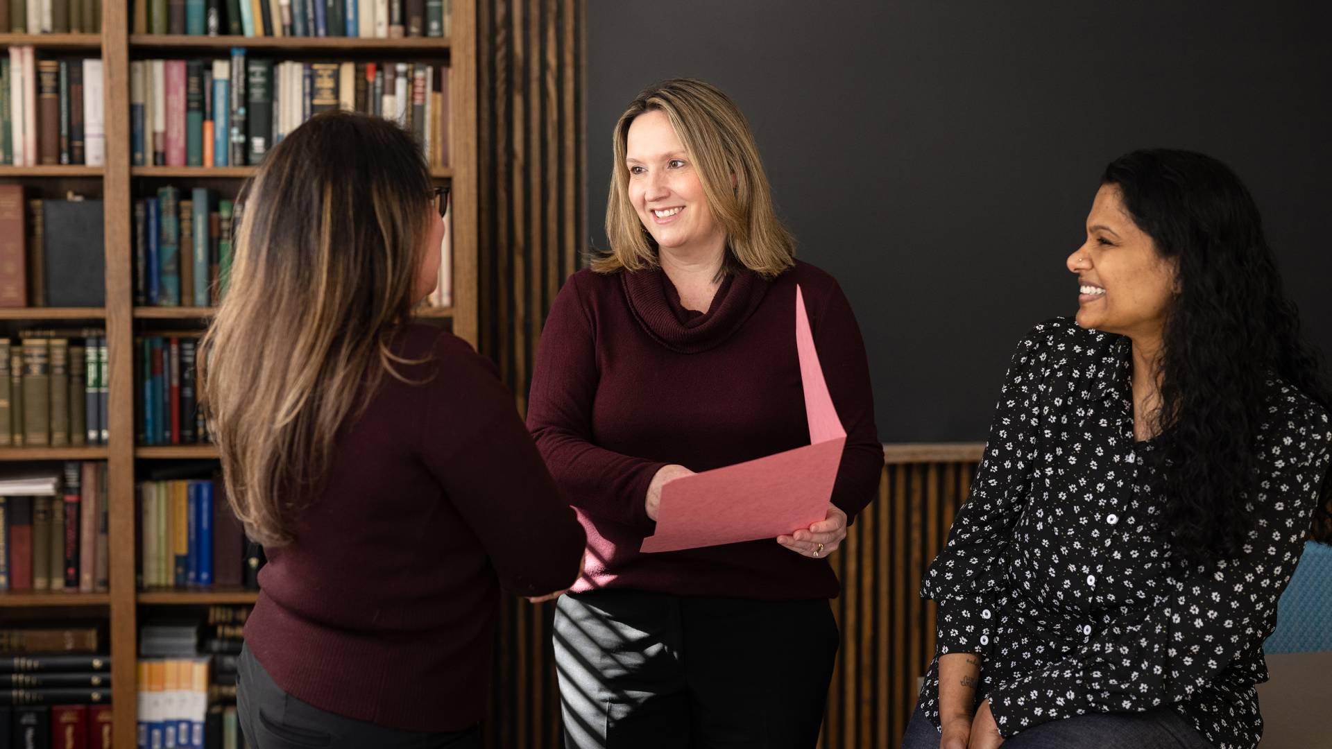 Three staffers confer in a meeting room.