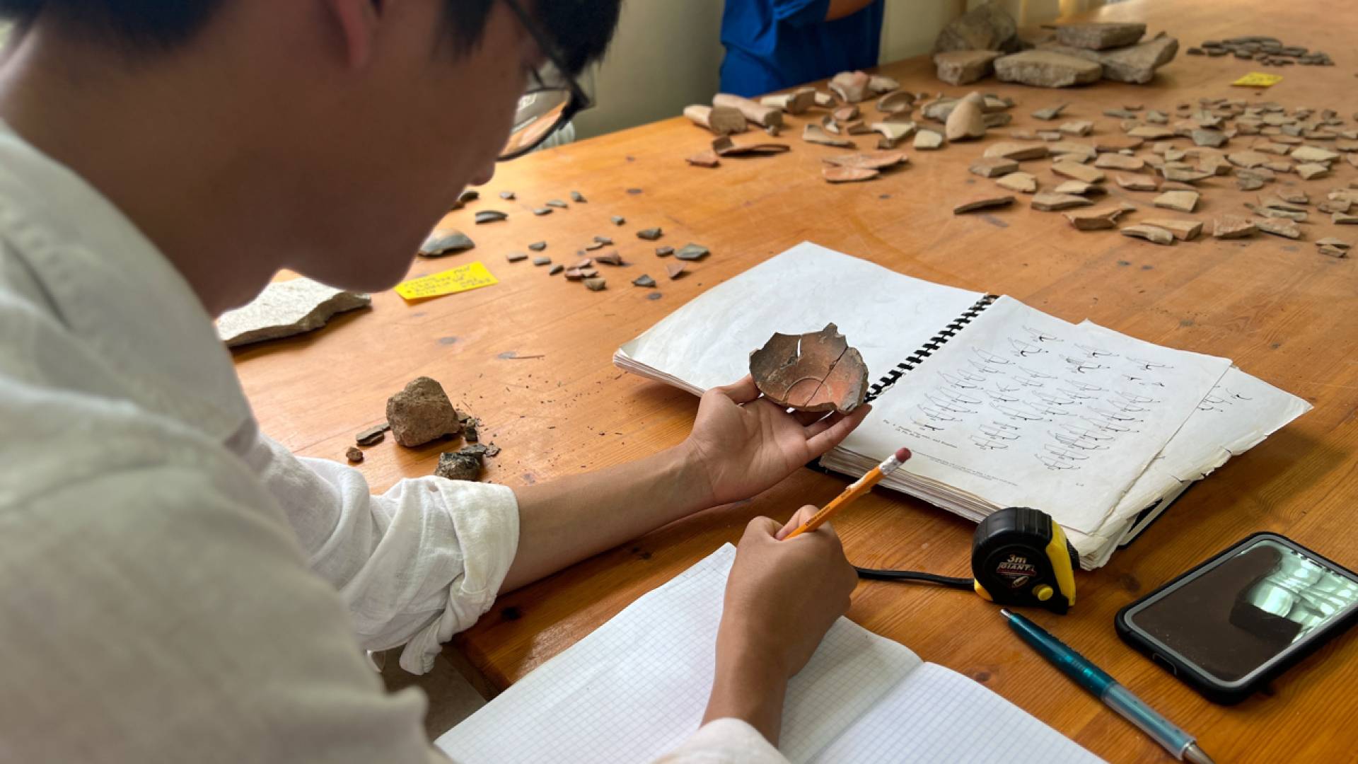 A student hold up a fragment of an ancient object.