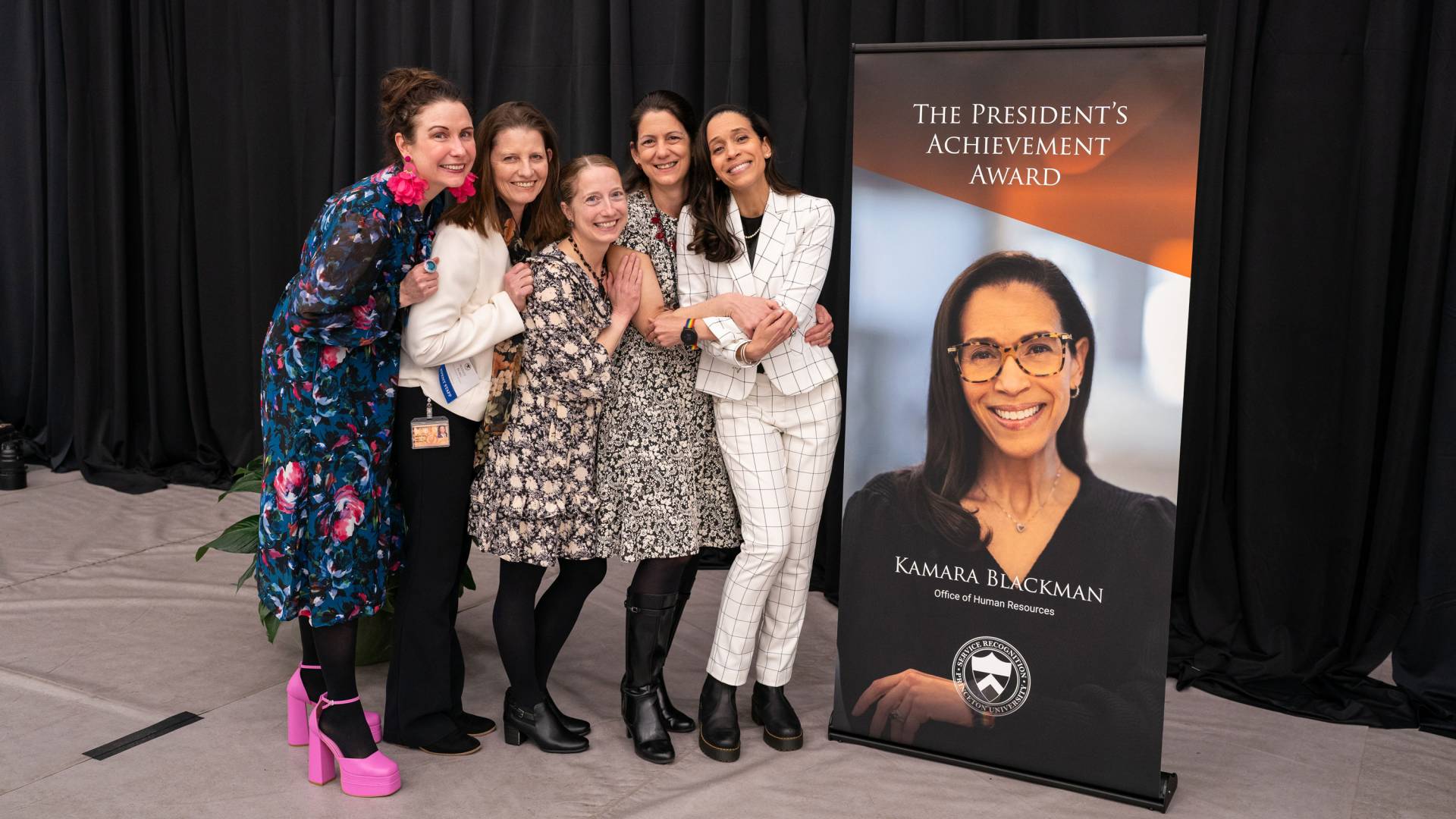 HR group posing with a colleague in front of her banner