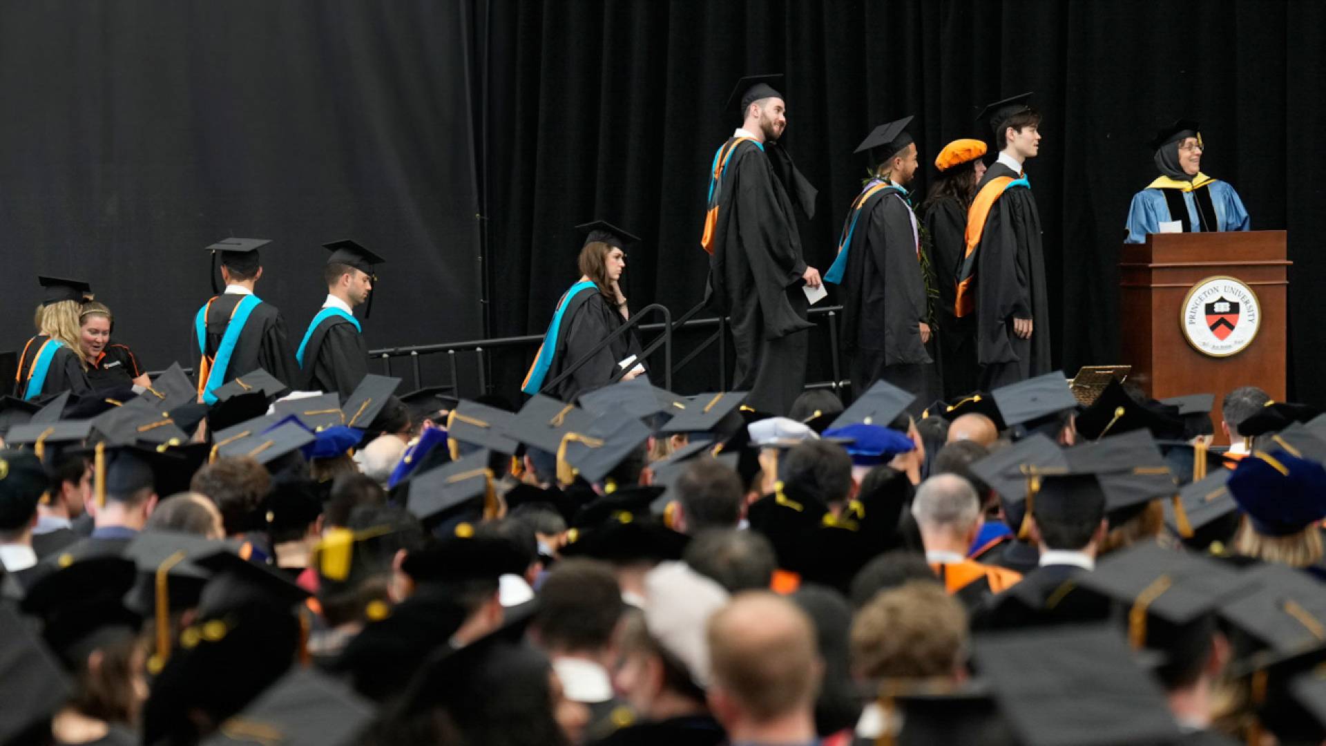 Master in Public Affairs and Master in Public Policy students line up, waiting for their names to be read by Amaney Jamal, dean of Princeton's School of Public and International Affairs (at podium).