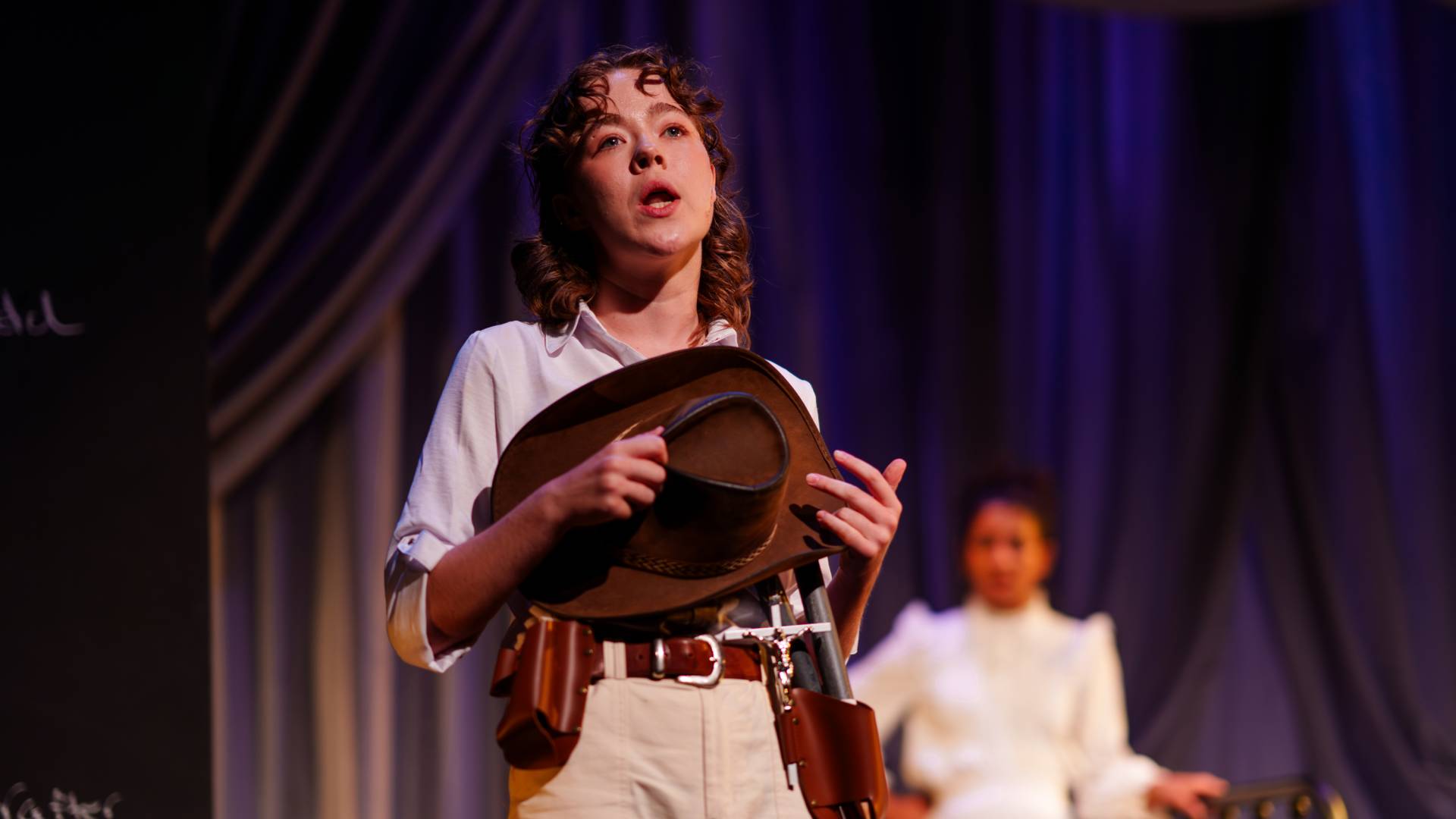 An actress recites dialogue while holding a cowboy hat