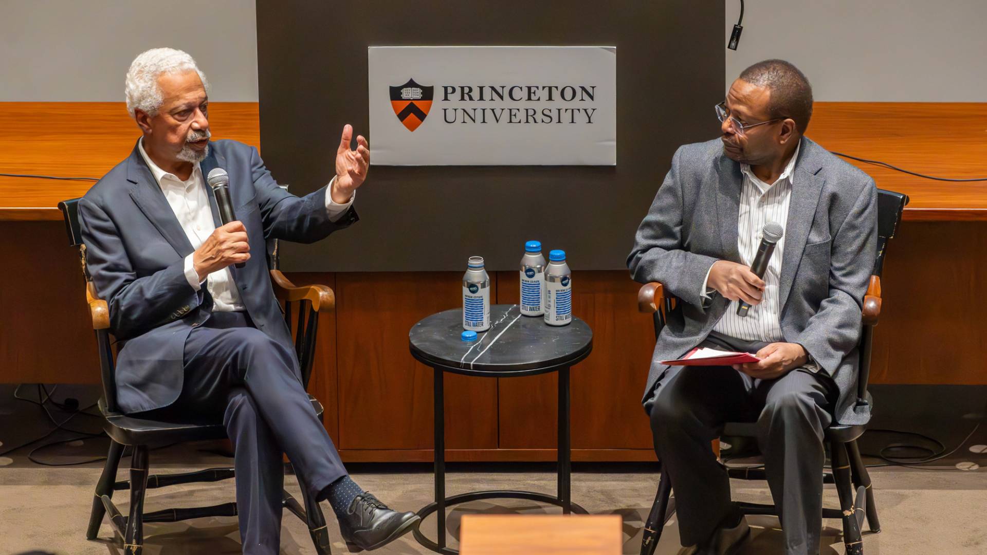 An auditorium filled with people listening to Abdulrazak Gurnah speaking with in front of everyone.