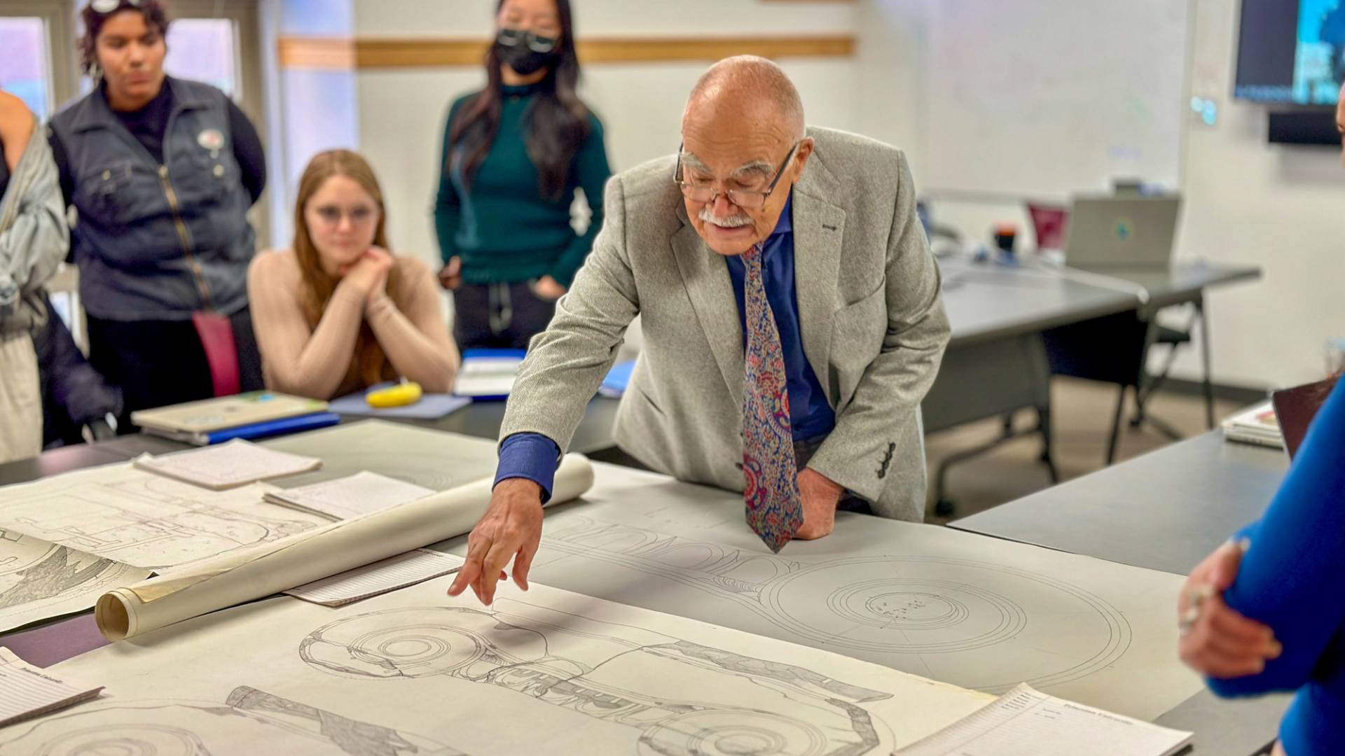 Nikos Makris explaining a document containing architectural drawings.