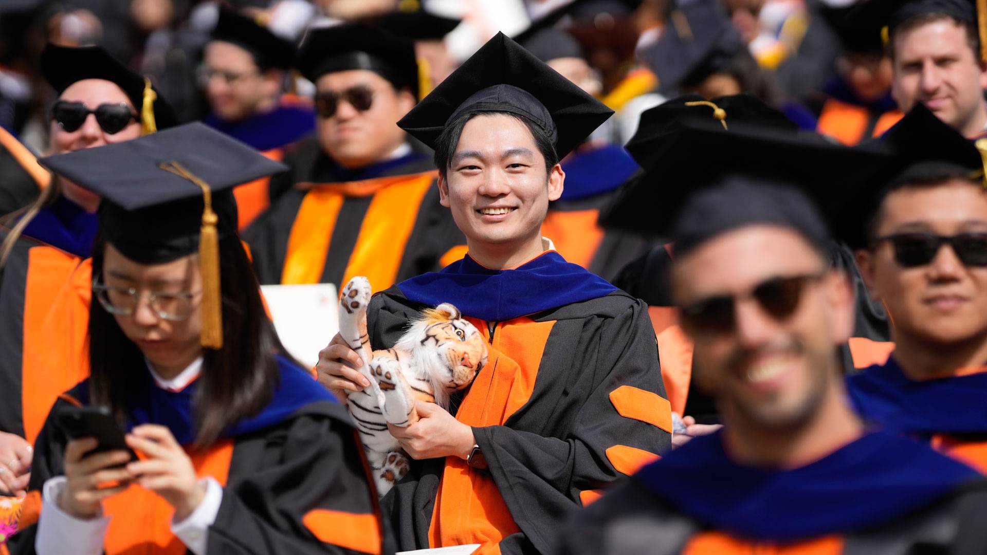 A graduating student holds a stuffed tiger