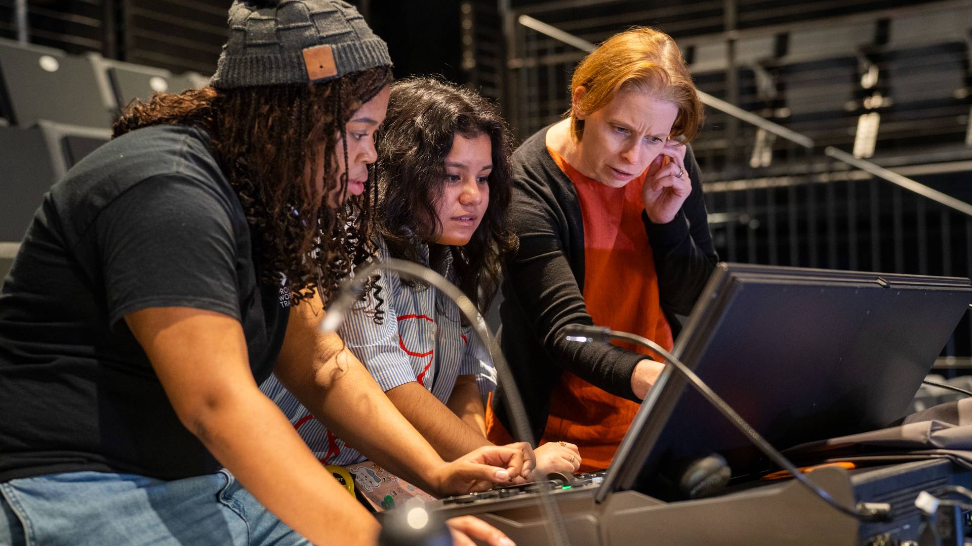 Two students at a lighting control with program director Tess James,