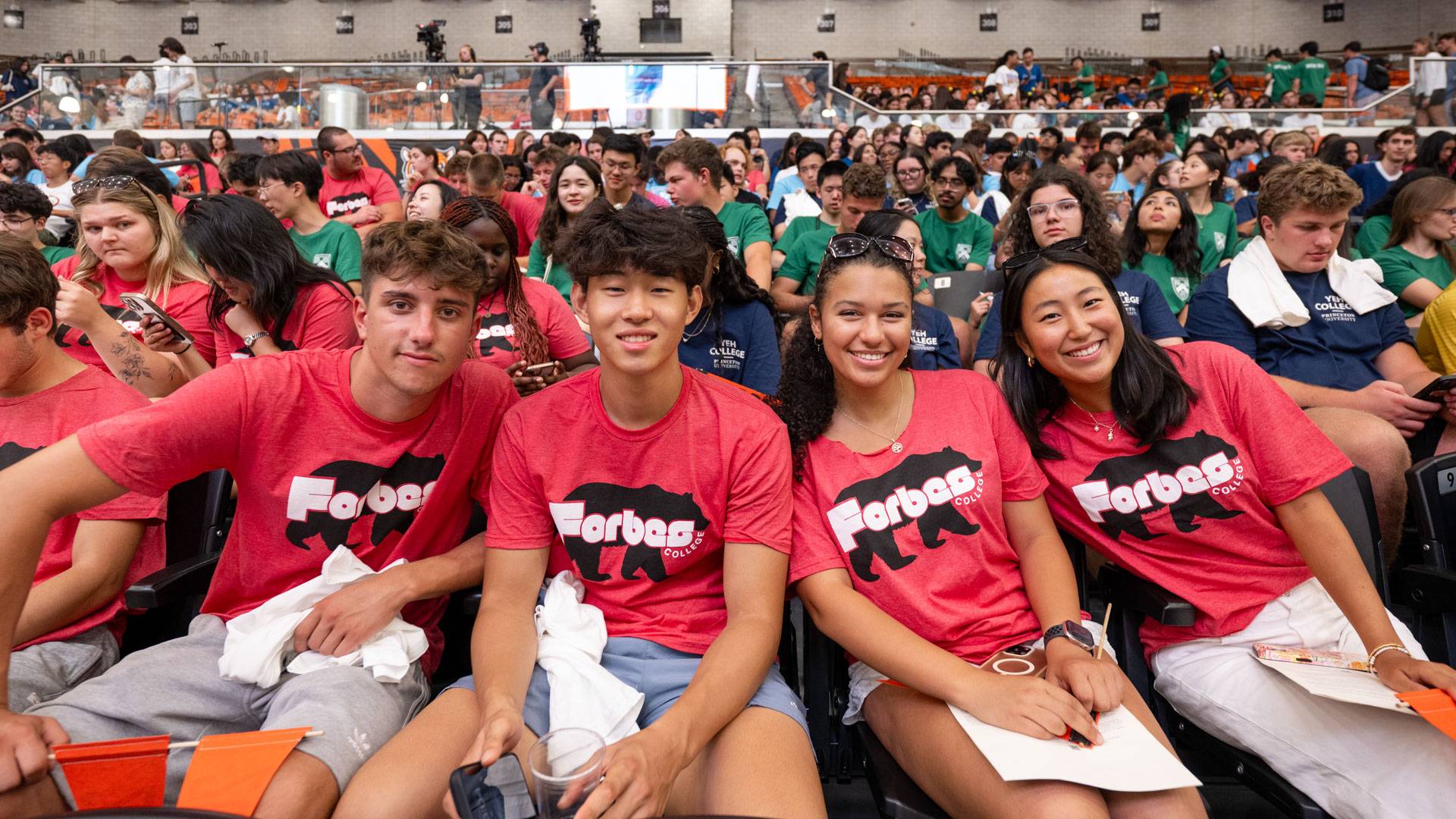 Students in red Forbes College teeshirts pose in Jadwin Gymnasium before the 2025 Pre-read assembly.