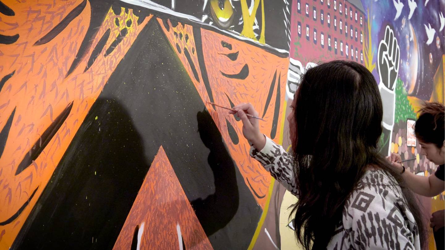 student painting mural for Butler College