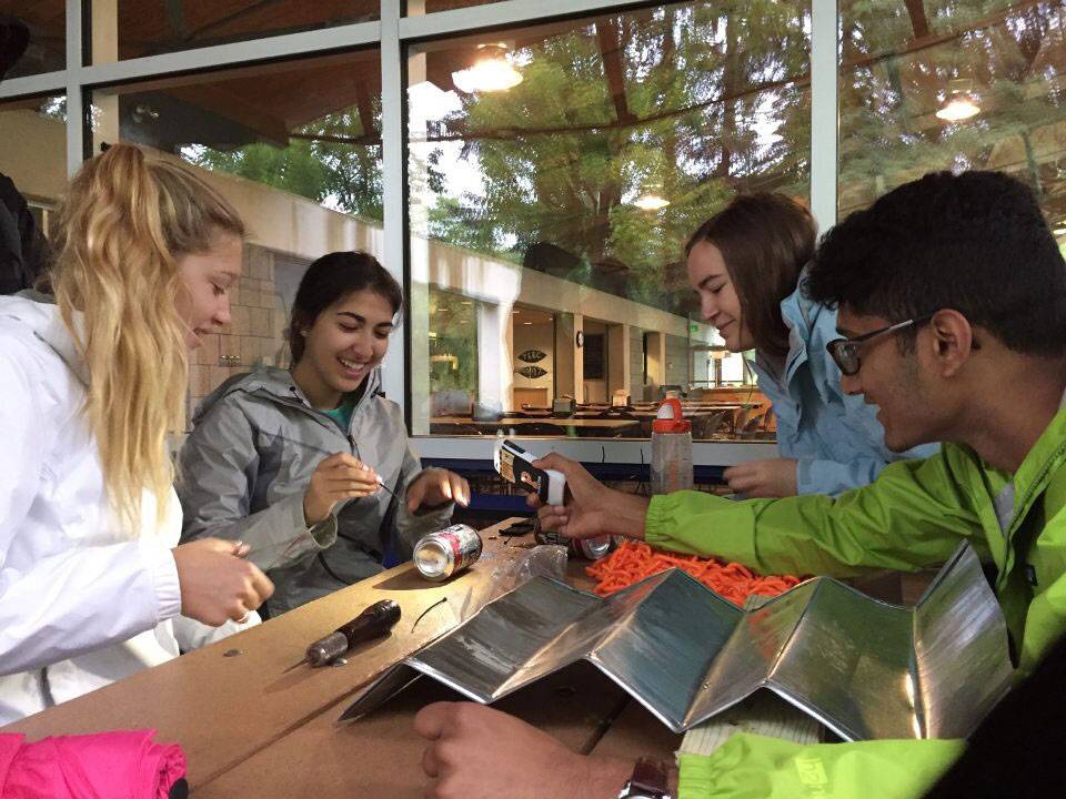 Students building a rain chain display from recycled soda cans and water bottles