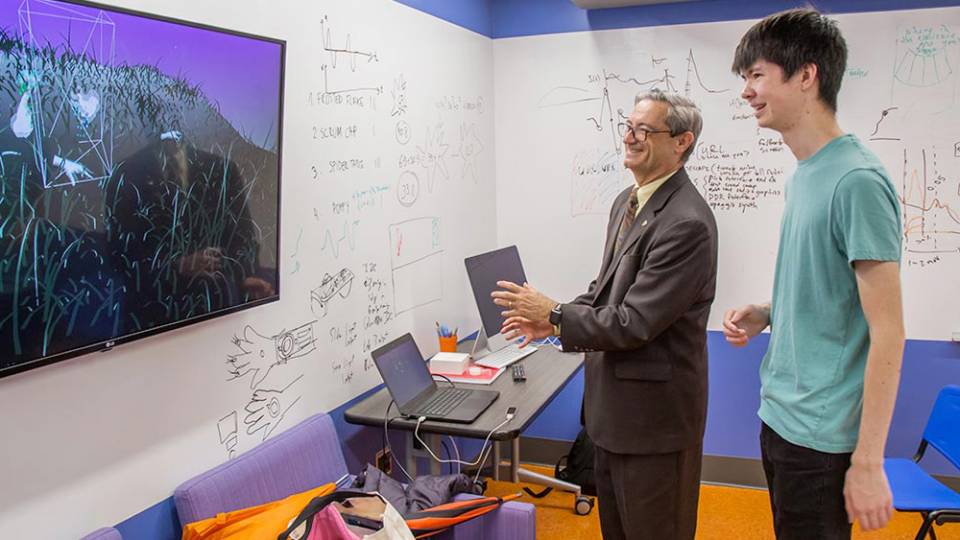 Student demonstrates motion-sensor to lab visitor