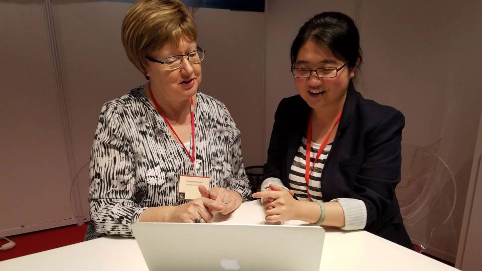 Catherine Peters and Hang Deng sit in front of computer