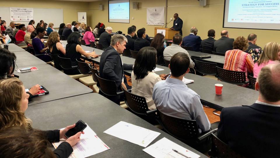 Audience listening to presenter at diversity summit vendor fair