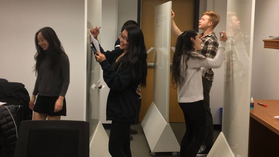 Students writing on movable whiteboards