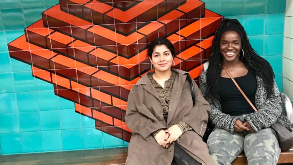 Two women sitting on a bench at a subway station