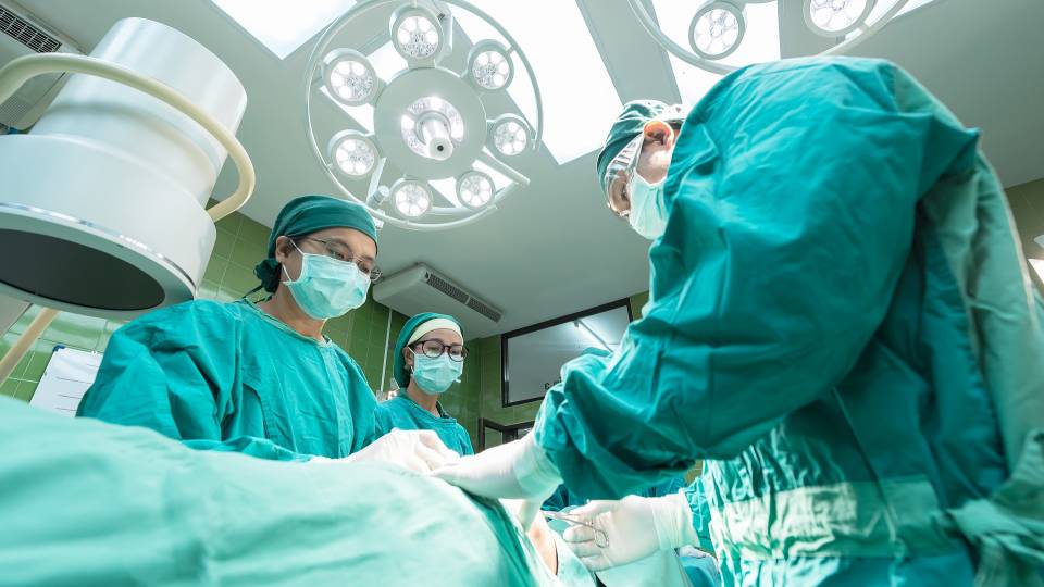 Three medical professionals in scrubs working in the operating room