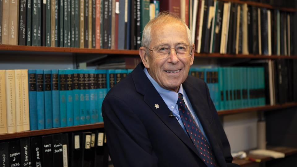 James Peebles in his office in front of books on a bookshelf