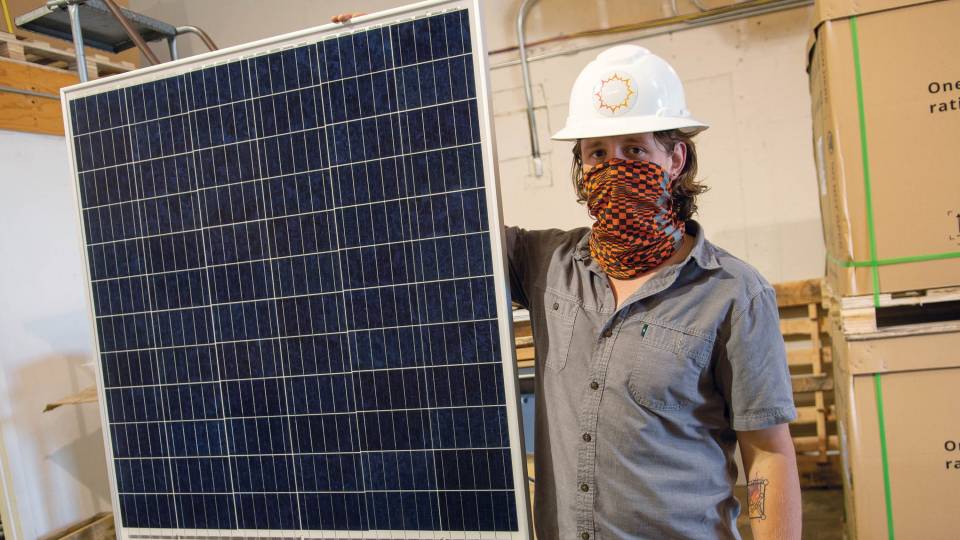 Angelo Campus stands next to a solar panel