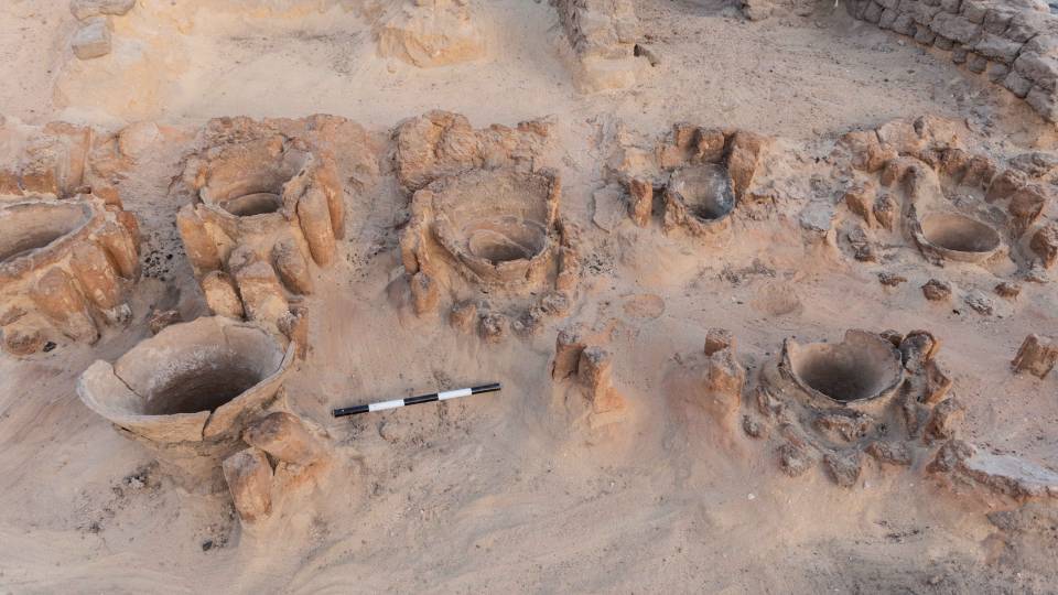 Openings of urns used to hold ingredients for brewing visible in the sand