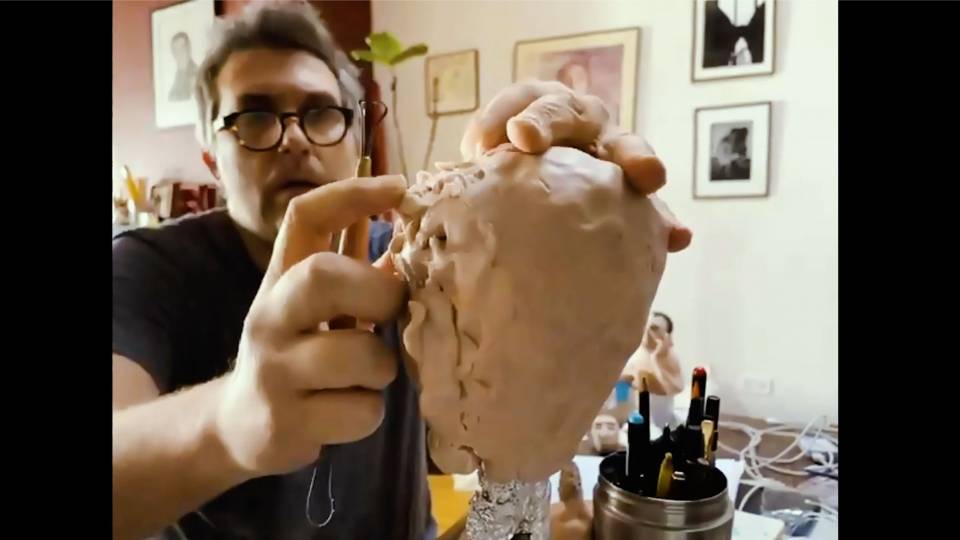 A man scupts a head from clay