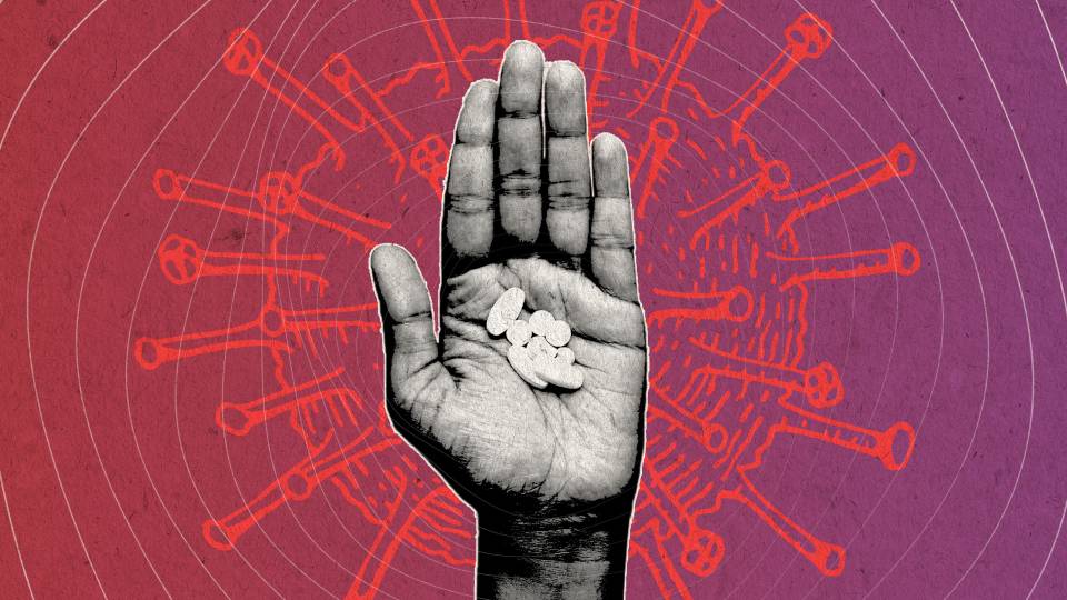 A hand holding pills in front of a drawing of a spiky coronovirus