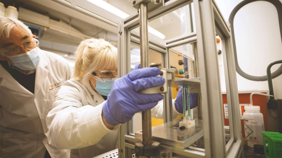 two researchers work with lab equipment