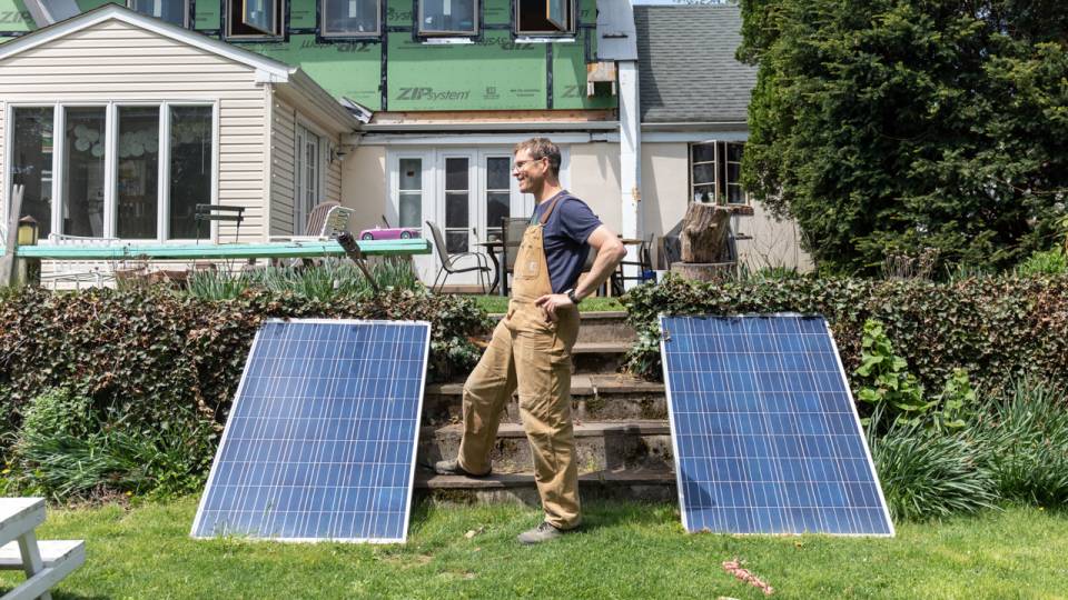 Forrest in front of his house under construction. Flanked by solar panels.