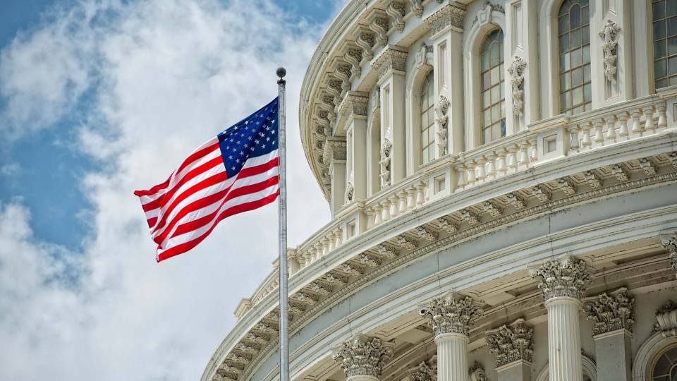 Waving US flag next to the Capitol building