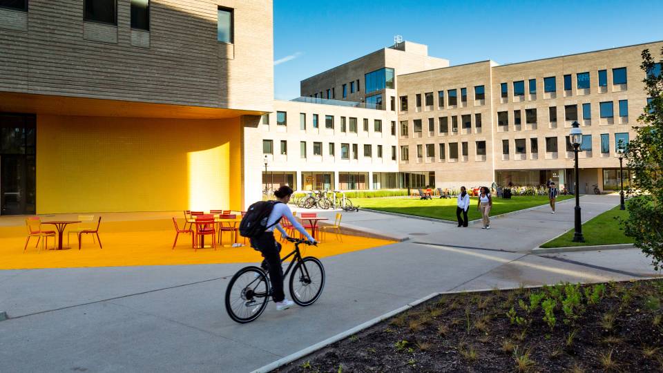 A student cycles through the new residential college area