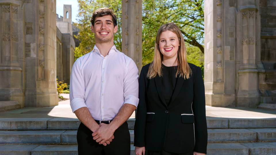 Smiling seniors Erik Medina and Rosie Eden stand together beneath one of Princeton's stone archways.