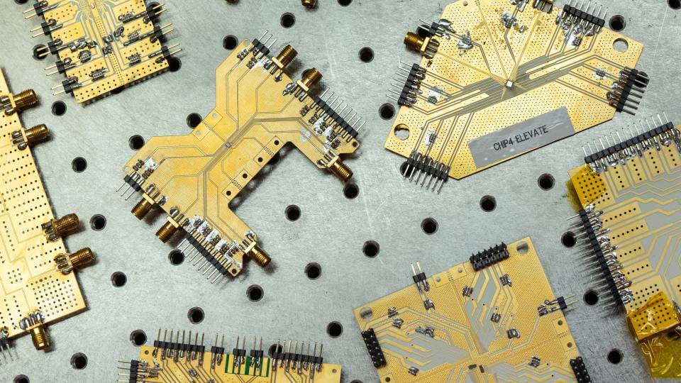 Several wireless chips, each with a different shape and different wiring pattern, sit on a workbench.