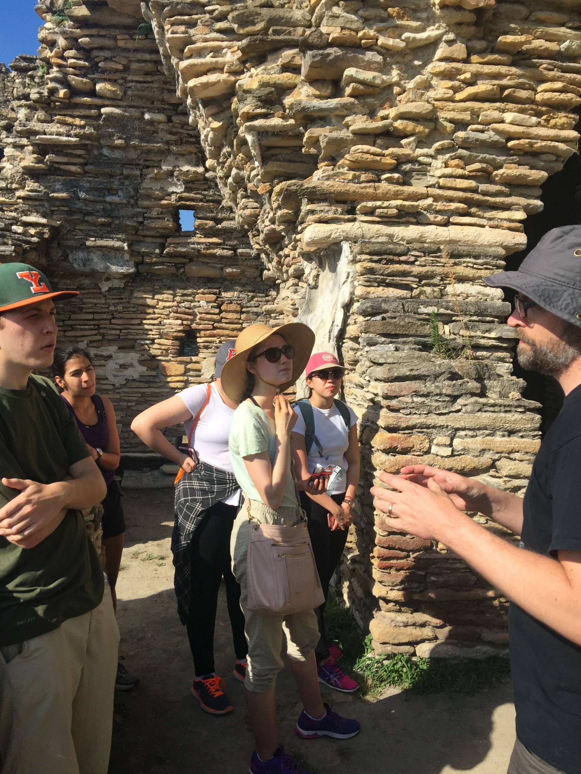 Students and professor amid palatial architecture of Tonina