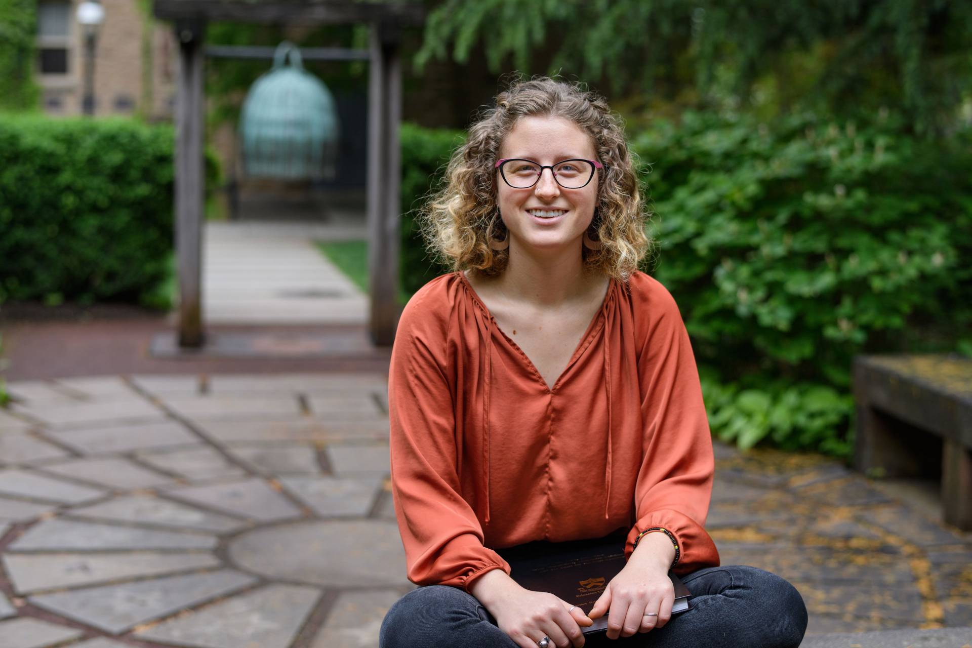 Amina Simon sitting by 9/11 memorial holding her senior thesis