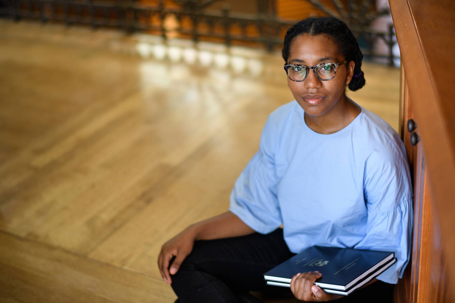 Rosed Serrano sitting on floor holding her senior thesis