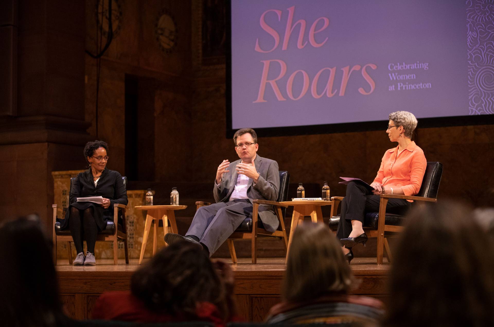 Carolyn Rouse, Keith Whittington and Michele Minter on stage with "She Roars" project on screen