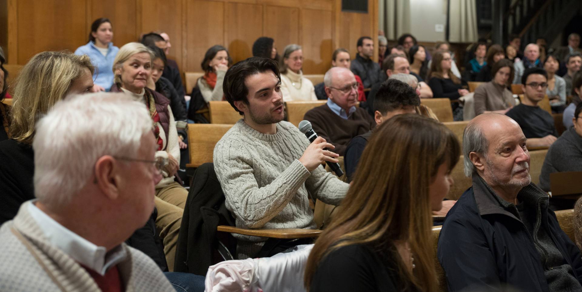 A young man asks a question into a microphone at an event