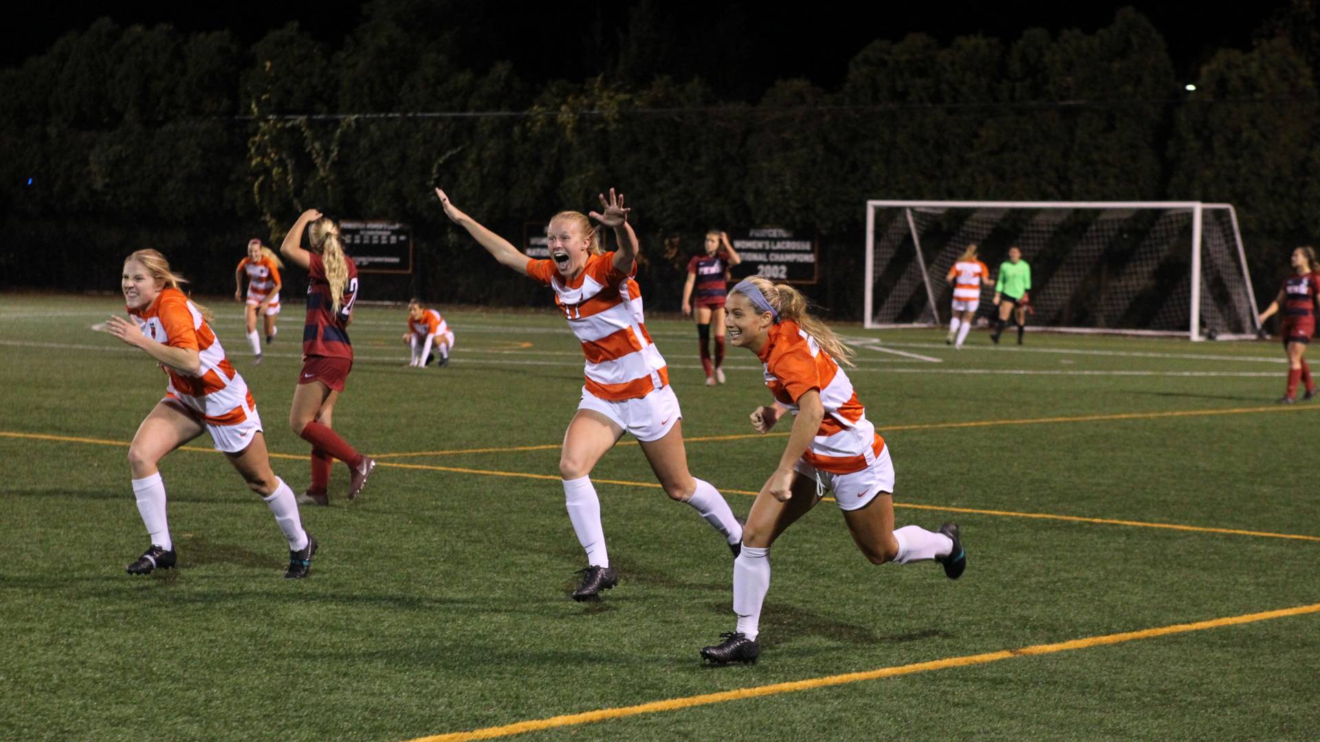 Women's soccer team celebrating on soccer field