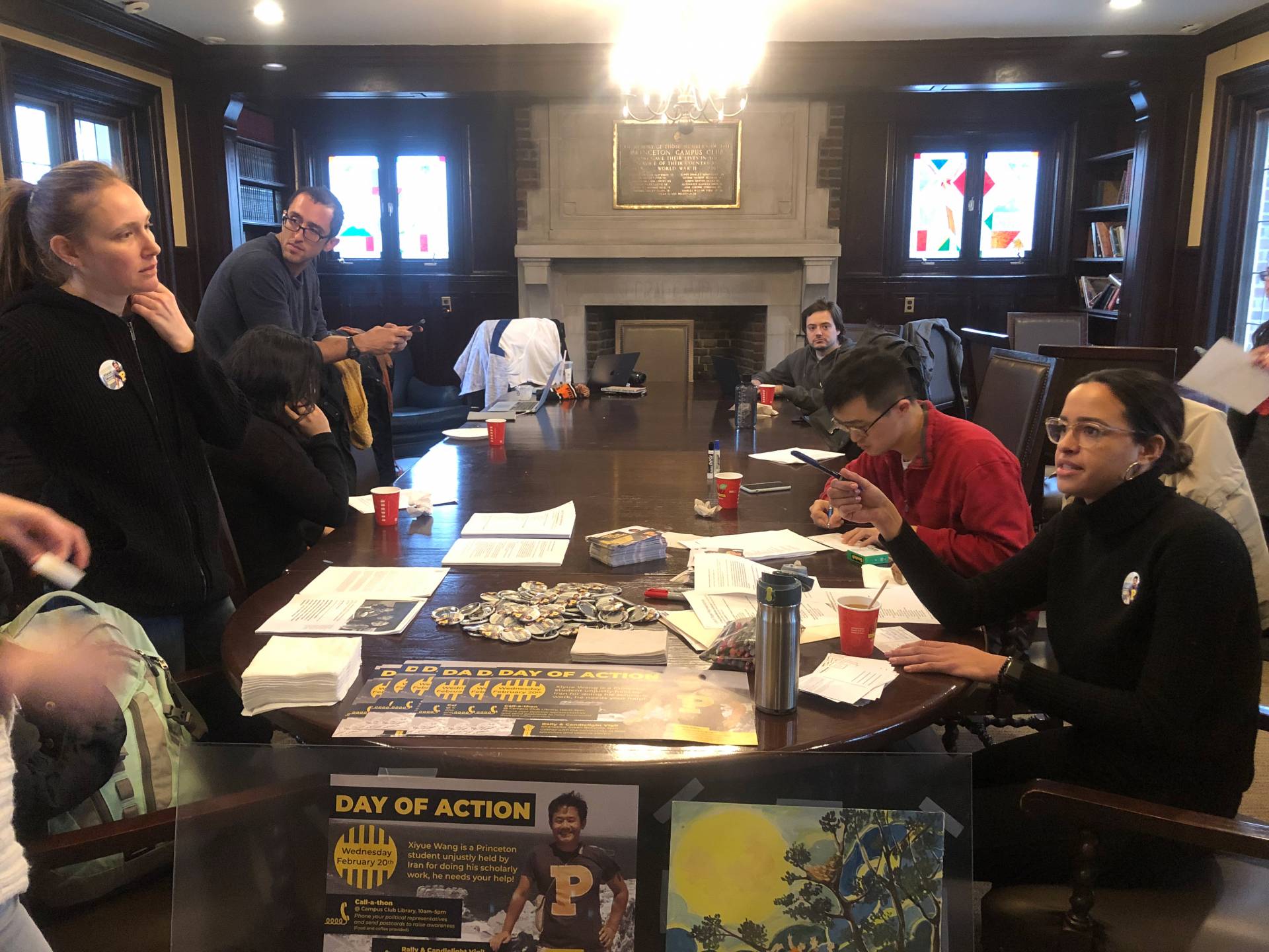 People around a table making calls, writing postcards and discussing how best to organize attendees